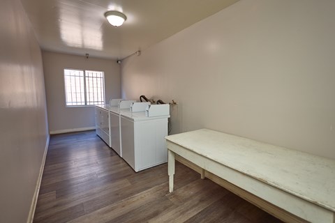 A room with a long table and a row of beds.