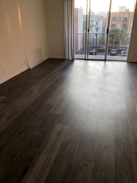 an empty living room with wood floors and a balcony