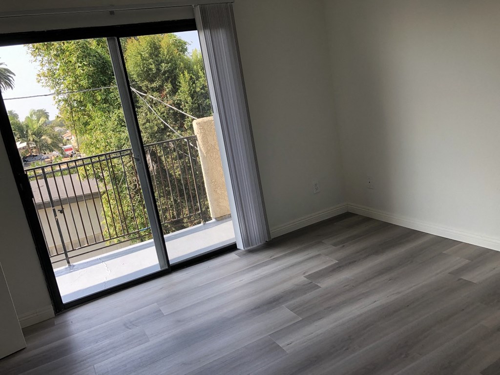 an empty living room with a sliding glass door to a balcony