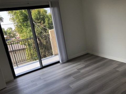 an empty living room with a sliding glass door to a balcony