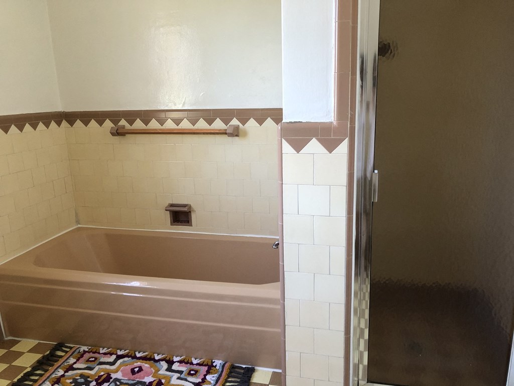 a bathroom with a tub and a tile floor and a shower
