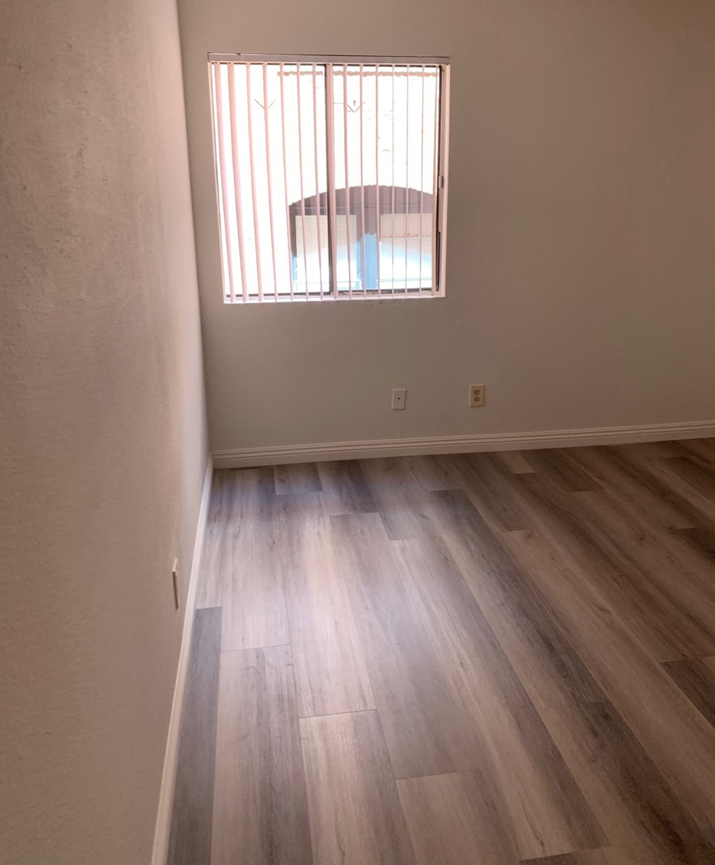 an empty room with wooden floors and a window