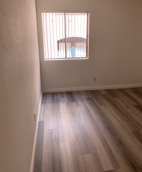 an empty room with wooden floors and a window