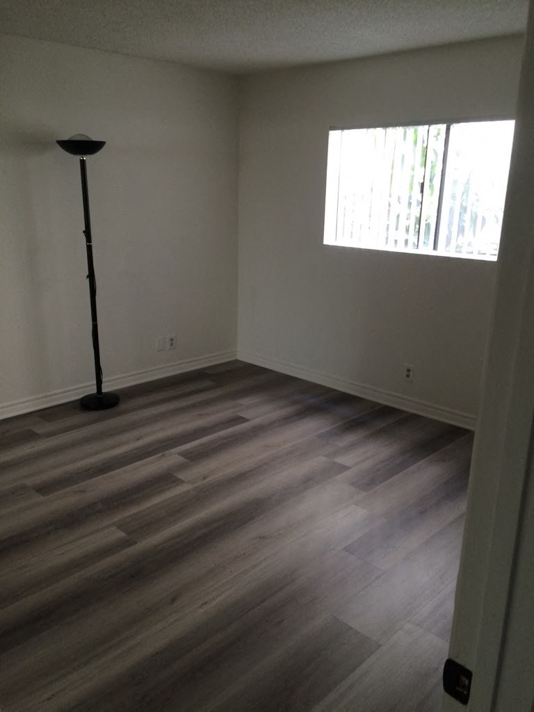 an empty living room with wooden floors and a window