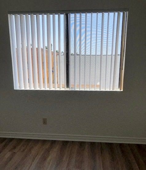 a window with white blinds in a room with wooden floors