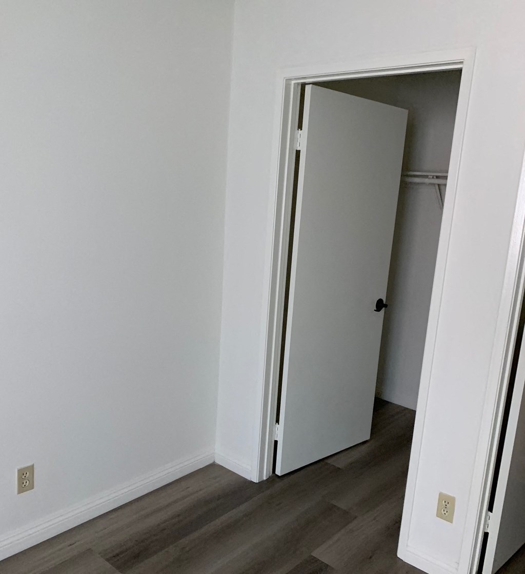 an open closet door in a room with white walls and a wooden floor