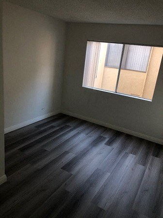 an empty room with a window and wooden floors