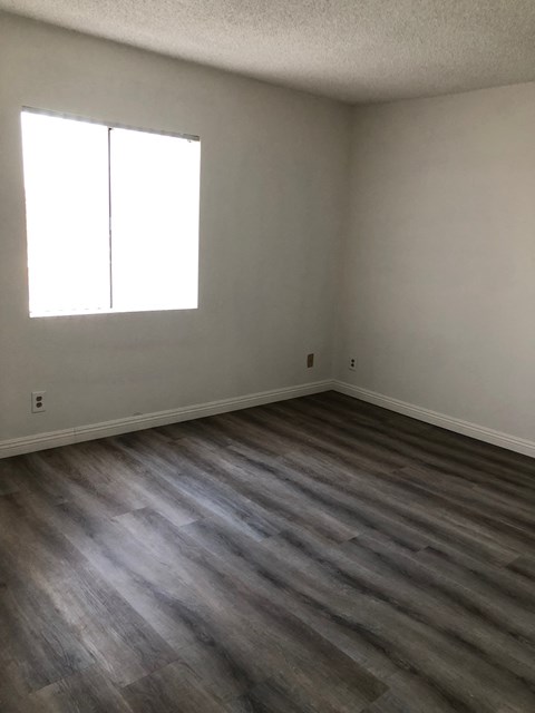 an empty room with wooden floors and a window