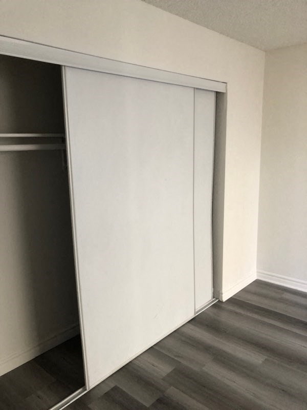a closet with a white wall and a wood floor