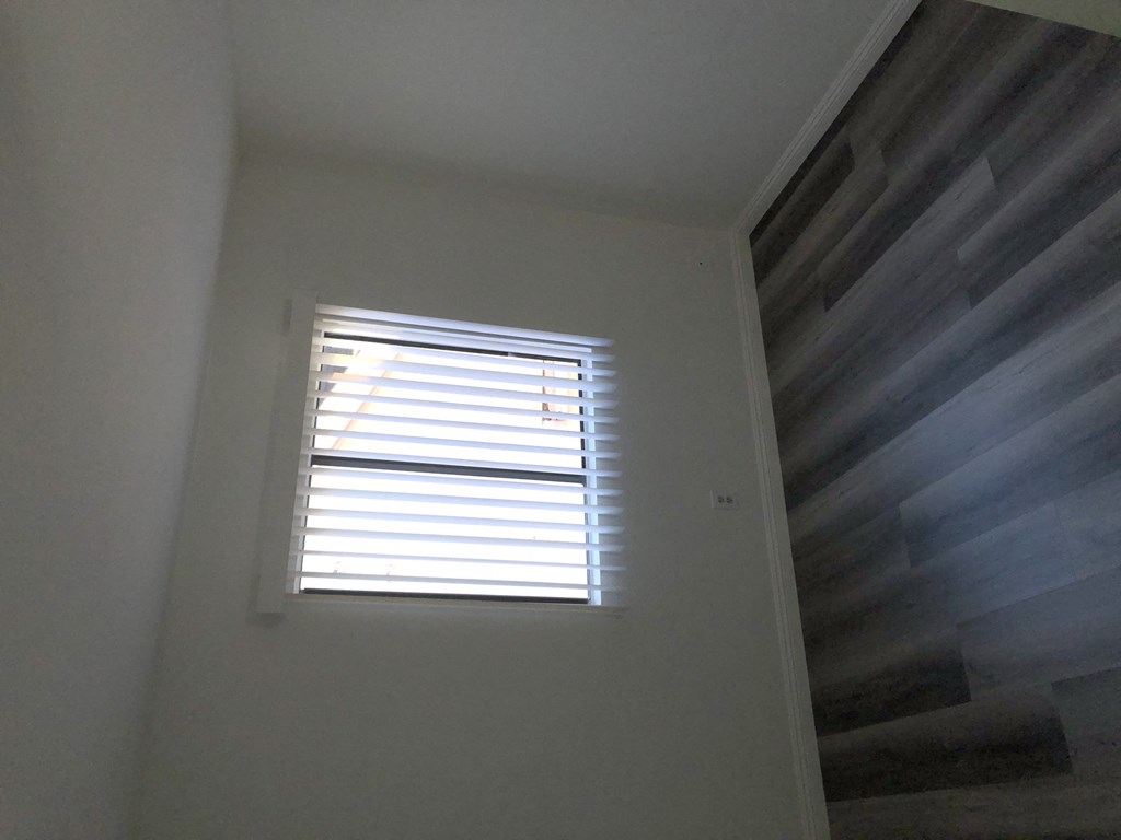 a window in the corner of a room with white walls