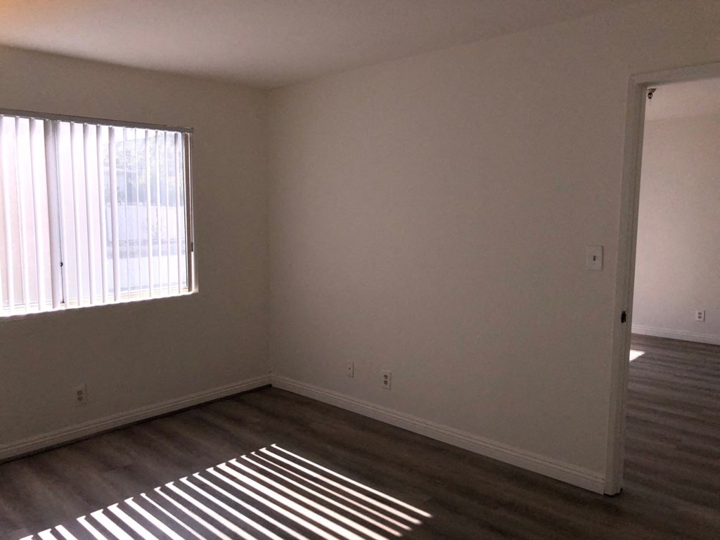 an empty room with wooden floors and a window