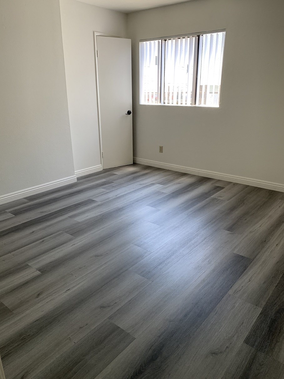 an empty living room with wood flooring and a window