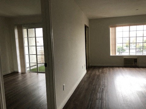 an empty living room with wood floors and a window
