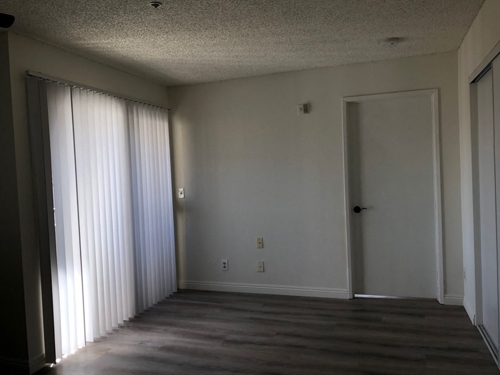 an empty living room with a large window and a door