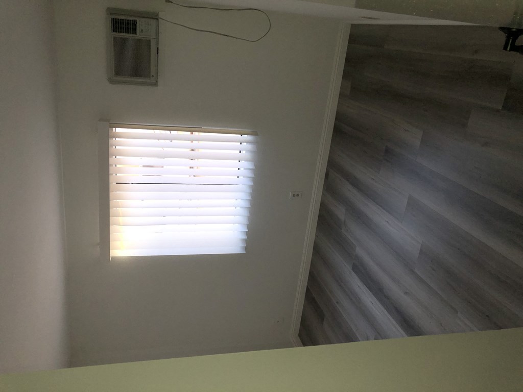 a window on a wall in a room with a wood floor