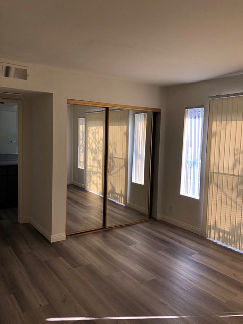 an empty living room with wooden floors and sliding glass doors