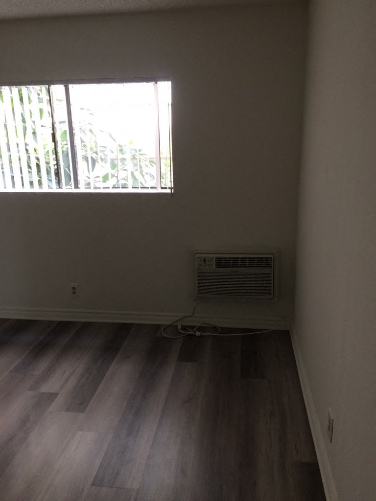 an empty room with a window and wooden floors