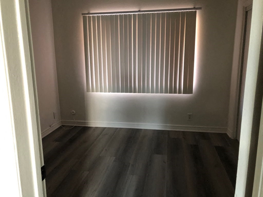 a room with wooden floors and a window with blinds