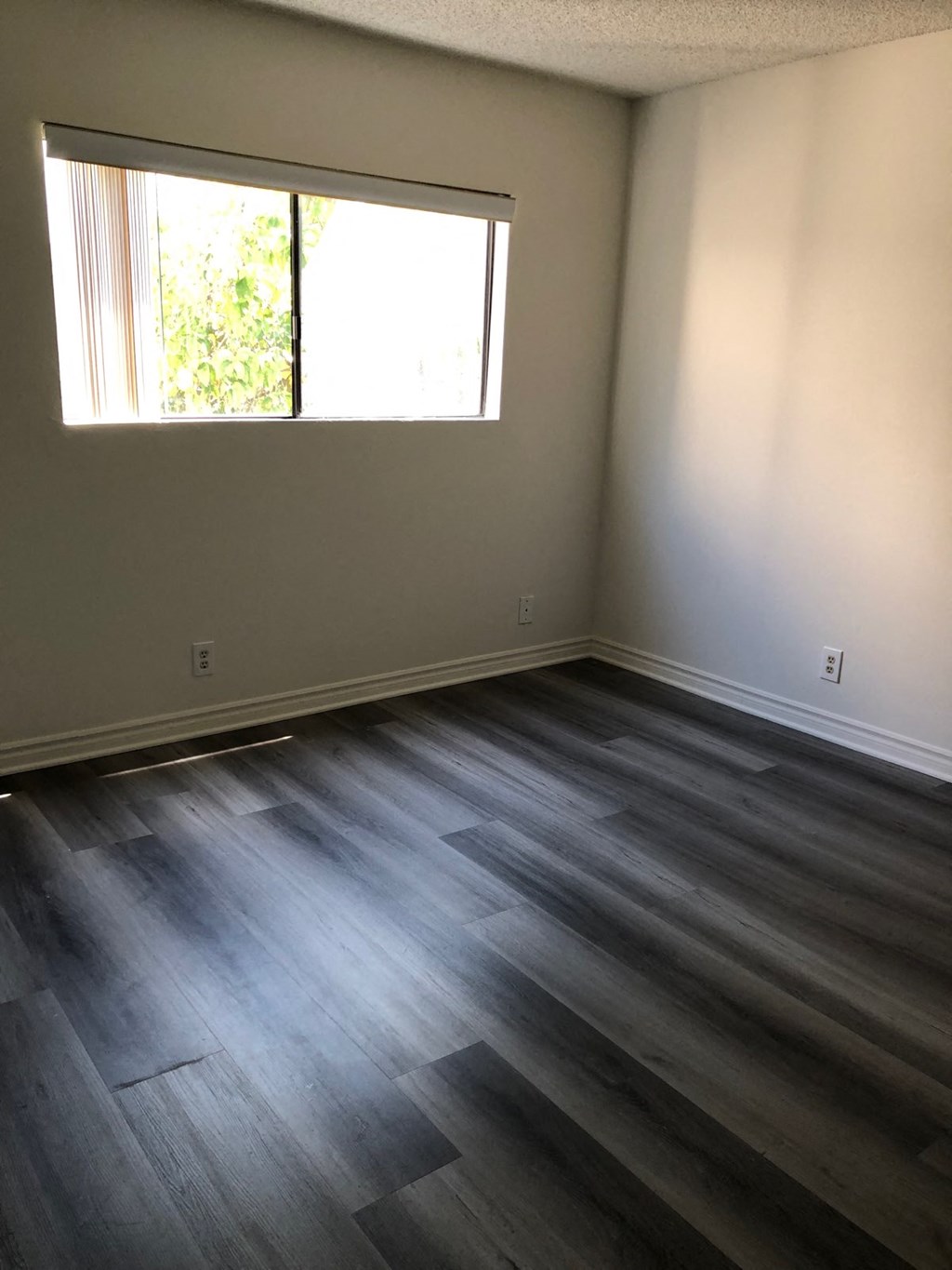 an empty room with wooden floors and a window