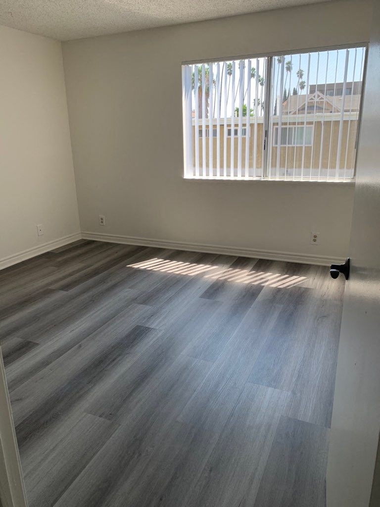 an empty living room with wood floors and a window