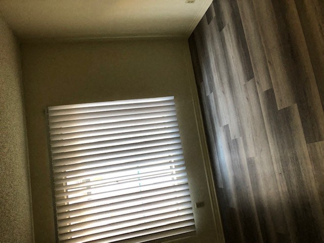 a window with white blinds in a room with wood floors