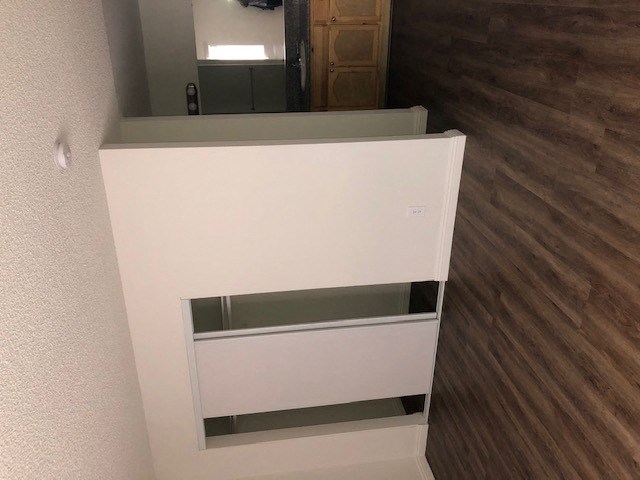 a white cabinet in a room with wood floors