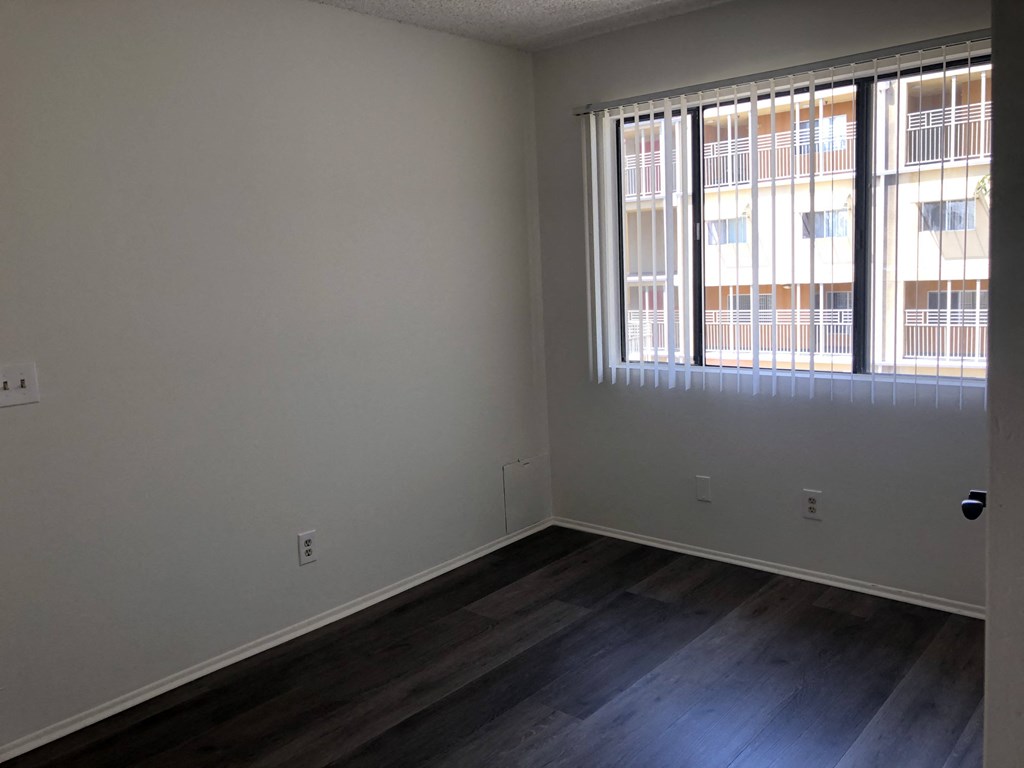 a bedroom with wood flooring and two windows