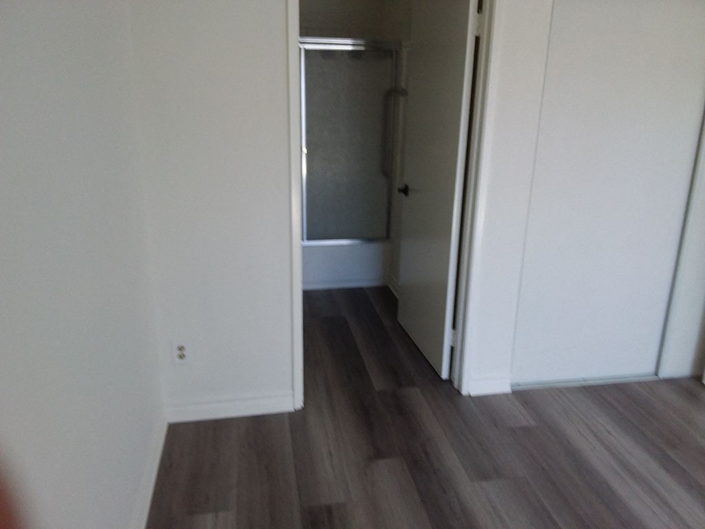 a closet in a white room with wooden floors and a door open