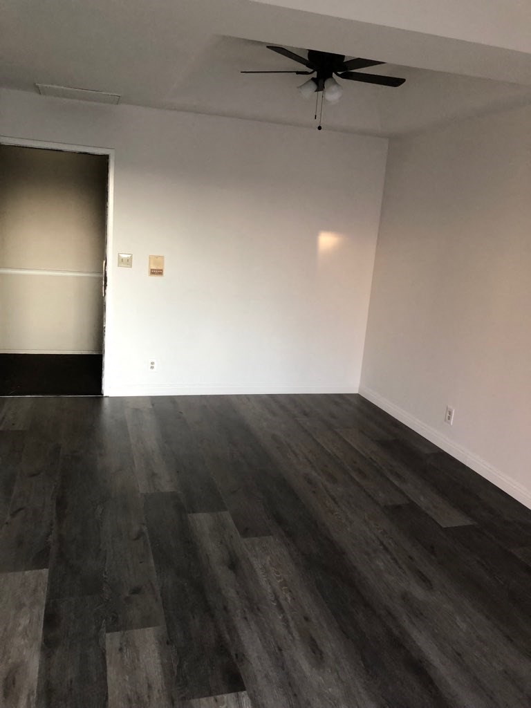 an empty living room with wood floors and a ceiling fan