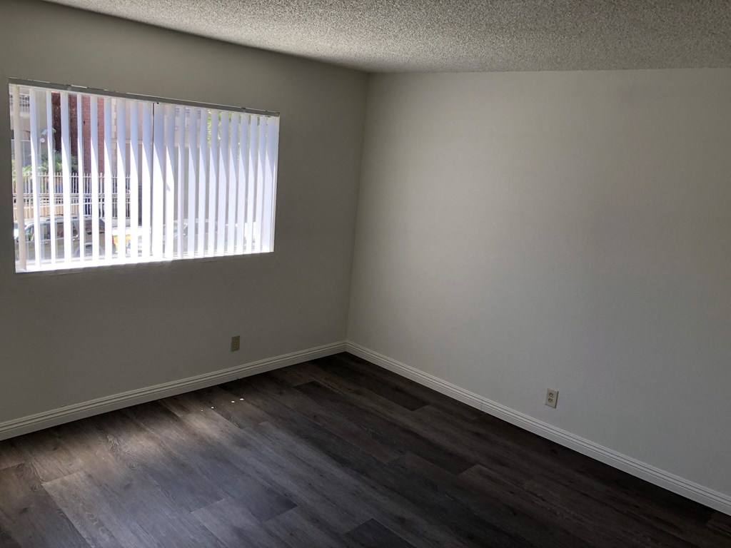 an empty room with wooden floors and a window