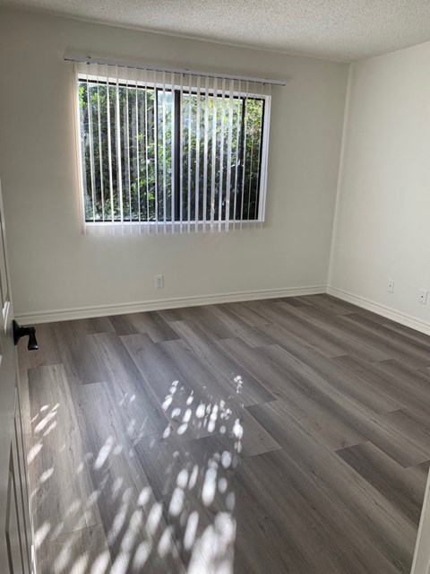 an empty room with wood floors and a window