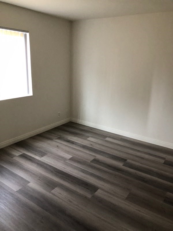 an empty room with wooden floors and a window