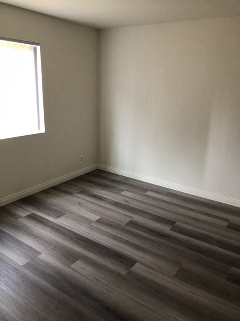 an empty room with wooden floors and a window