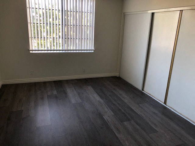 an empty living room with wood floors and a window