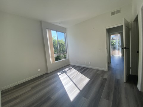 an empty living room with wooden floors and a window