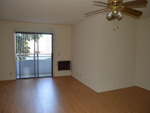 an empty living room with a ceiling fan and a sliding glass door