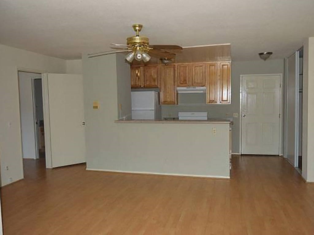 an empty living room and kitchen with a ceiling fan