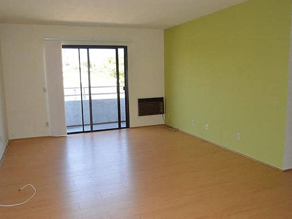 an empty living room with a wood floor and a glass door