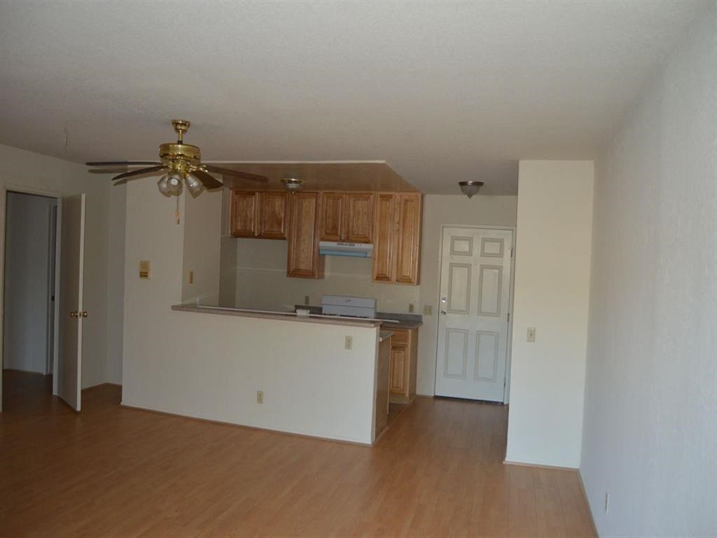 an empty living room and kitchen with a ceiling fan