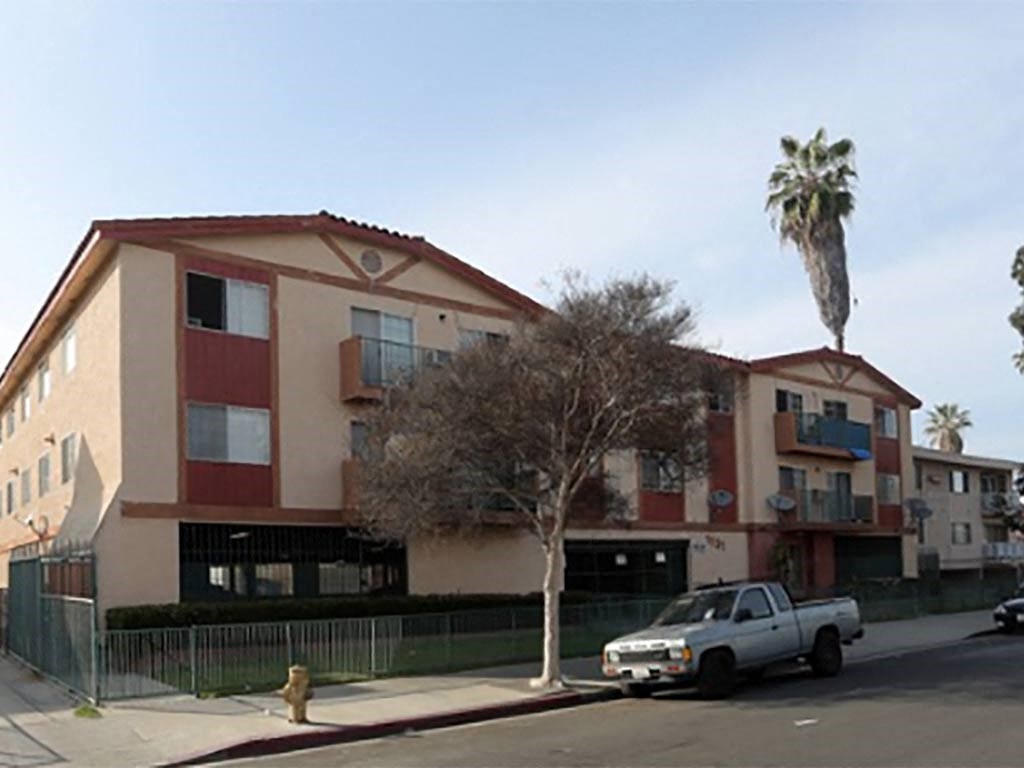 an apartment building with a palm tree and a truck parked in front