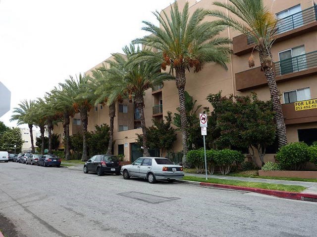 a street with cars parked in front of an apartment building