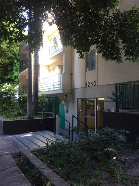 the front of an apartment building with trees and a sidewalk