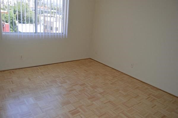 an empty room with a window and a wooden floor