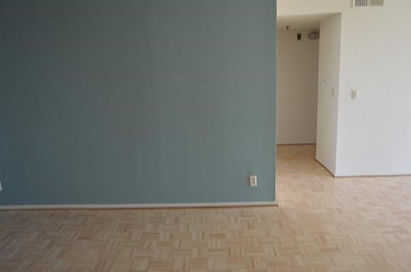 an empty room with a blue wall and a wooden floor