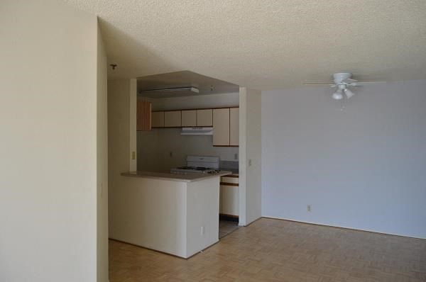 an empty room with a kitchen and a ceiling fan