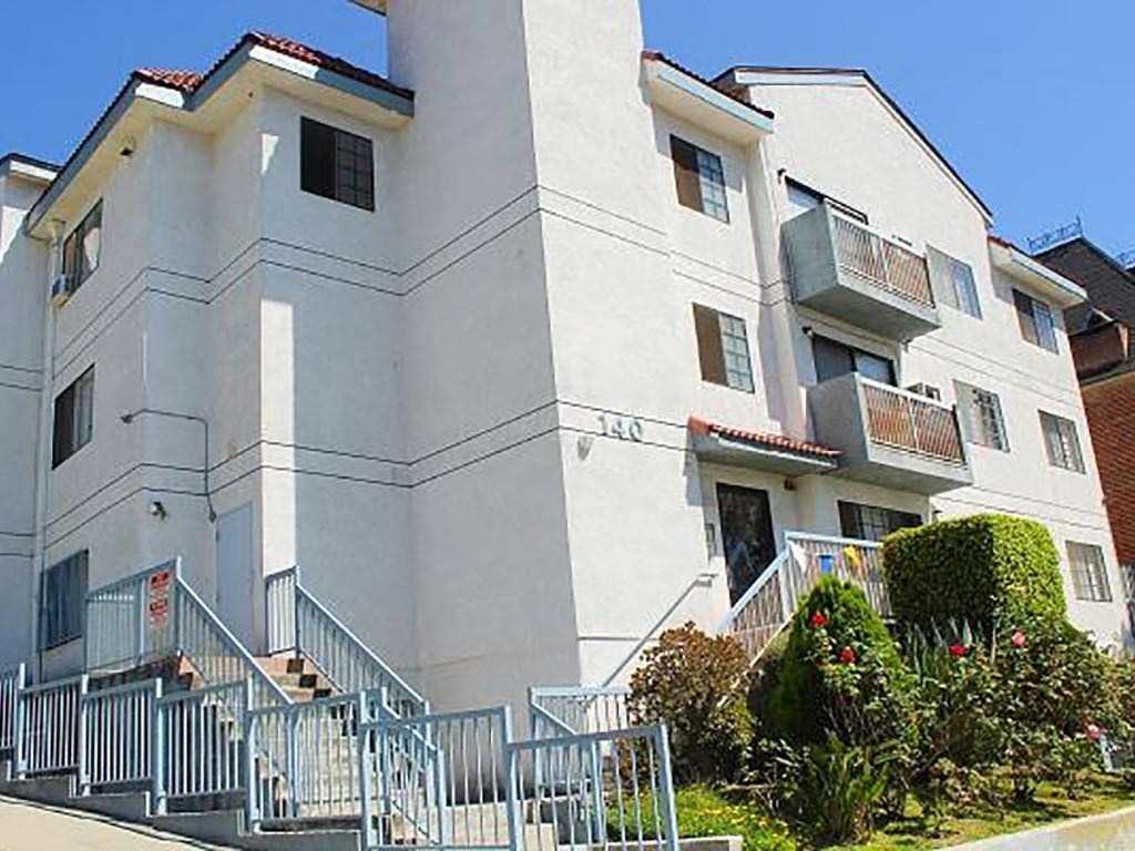 a white apartment building with stairs and a fence