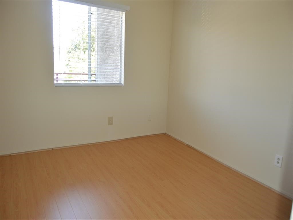 an empty room with a window and wooden floors