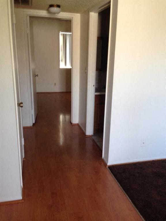 a hallway with a hard wood floor and white walls