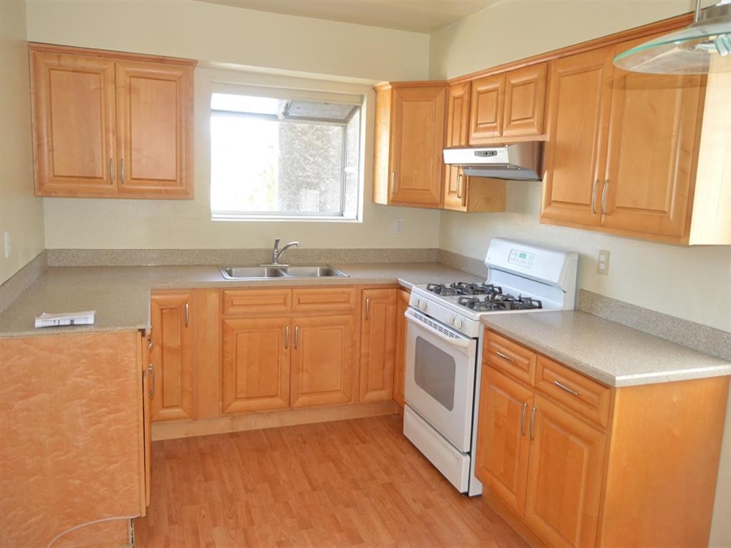 an empty kitchen with wooden cabinets and white appliances