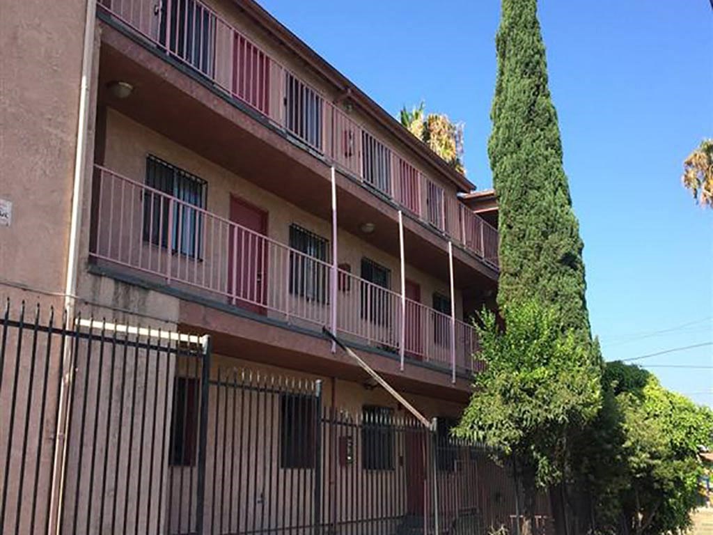 an apartment building with a tree and a fence